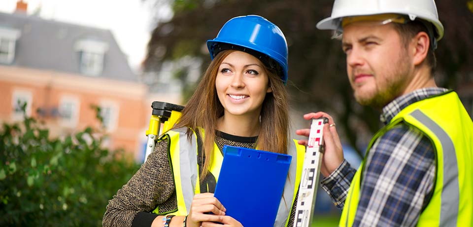 Two people outside wearing hard hats